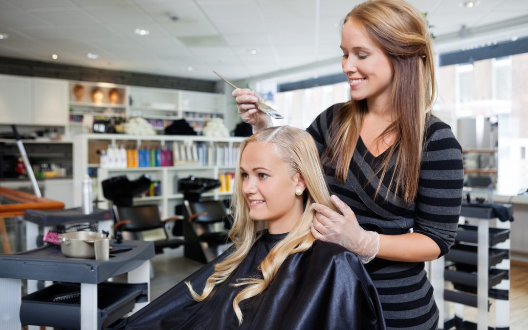 Young woman having her hair dyed by beautician at parlor