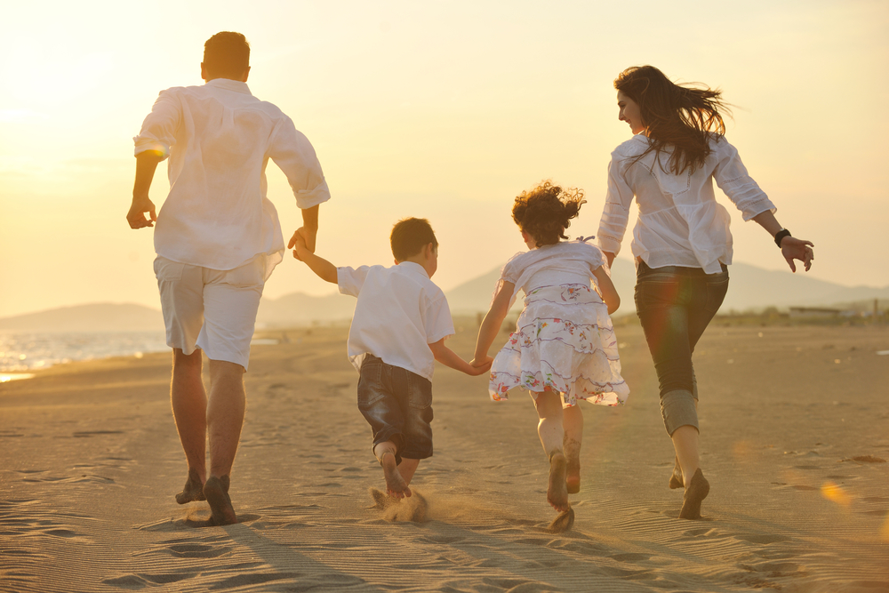 happy young family have fun on beach run and jump at sunset