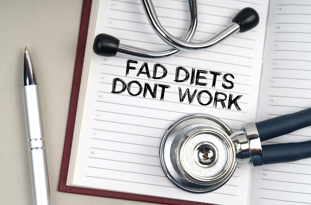 Medicine concept. On the table is a stethoscope, a pen and a notebook in which it is written - Fad Diets Dont Work