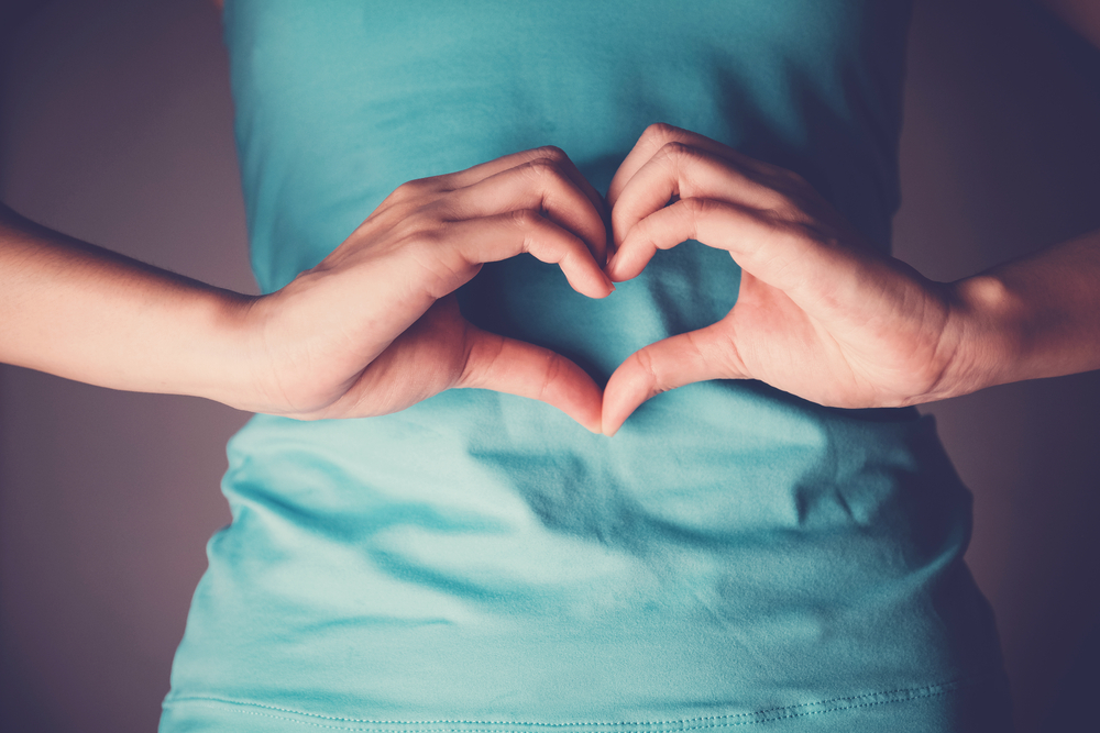 Woman hands making a heart shape on her stomach, healthy bowel degestion, probiotics for gut health