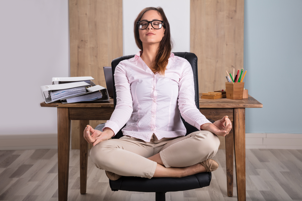 Young Businesswoman Sitting On Chair Meditating In Office
